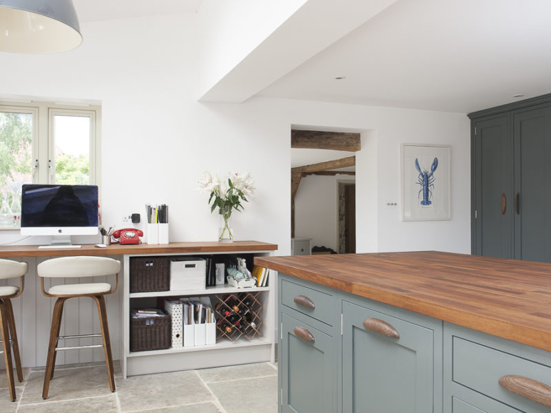 green kithen with wood worktops and stone floor