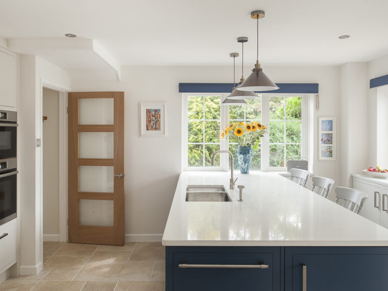 light airy kitchen with blue island and white worktops