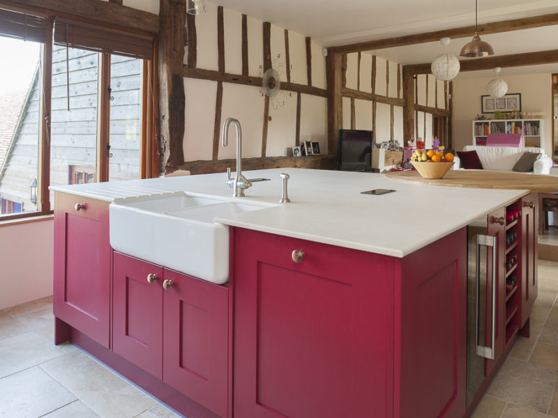 red kitchen island with belfast sink and beams