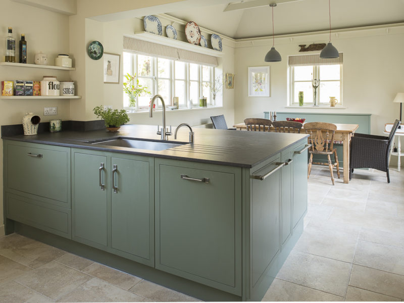 green kitchen island with tiled floor and pendant lights