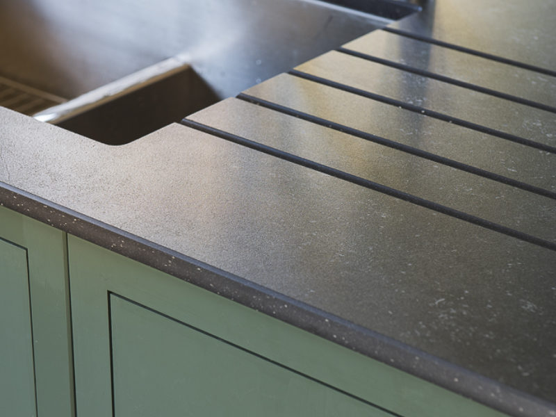 green kitchen with swan neck tap and dark worktops