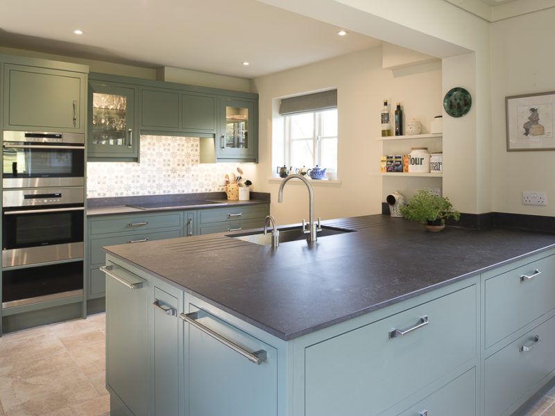 green kitchen with island and dark worktops