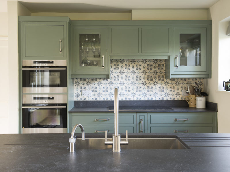 green kitchen with tiled splashback